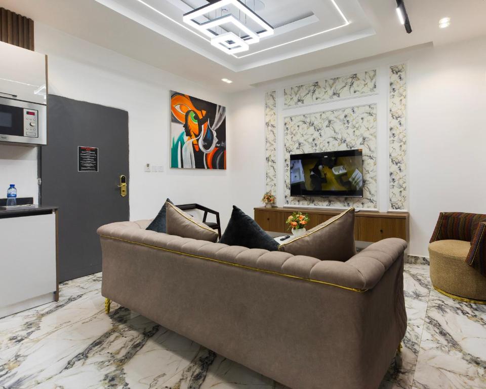 a living room with a brown couch and a kitchen at Nuelin Luxury Apartments 1bed in Mama