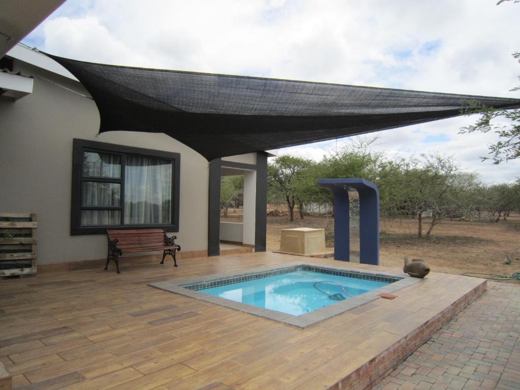 a patio with a swimming pool and a mosquito net at Nathi Kruger View Guest House in Marloth Park