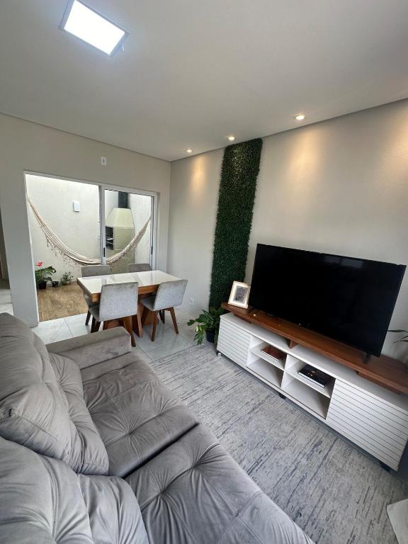 a living room with a large flat screen tv at Casa de 2 dormitórios com piscina in Pelotas