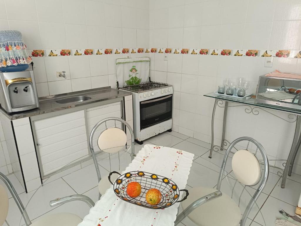 a kitchen with two chairs and a basket with oranges in it at Apartamento Amplo e familiar em frente à Igreja do Céu in Viçosa do Ceará