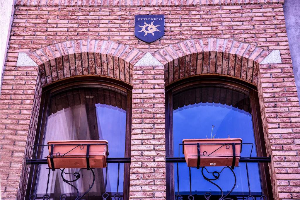 dos ventanas con un reloj en el lateral de un edificio de ladrillo en B&B Casa Federico en San Giovanni in Fiore