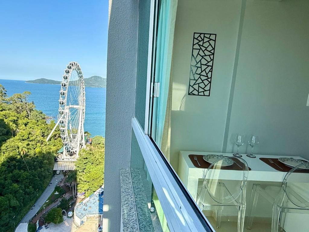 a balcony with a table and a ferris wheel at Flat - Frente Mar, Roda Gigante e Estrada da Rainha in Balneário Camboriú