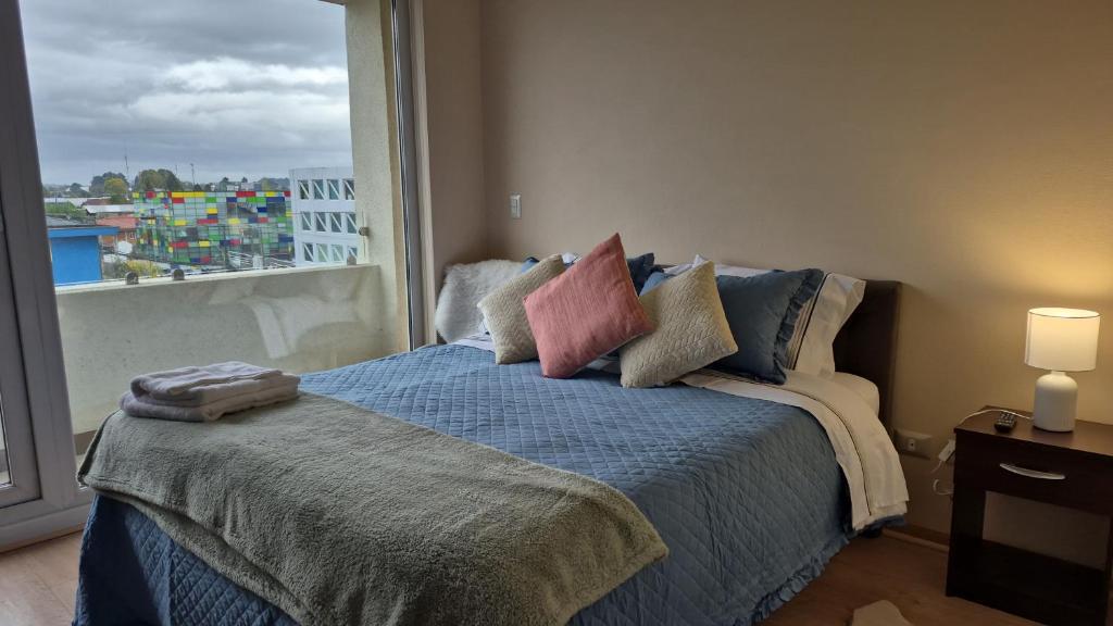 a bedroom with a bed with a large window at Departamento Central Osorno 2 in Osorno