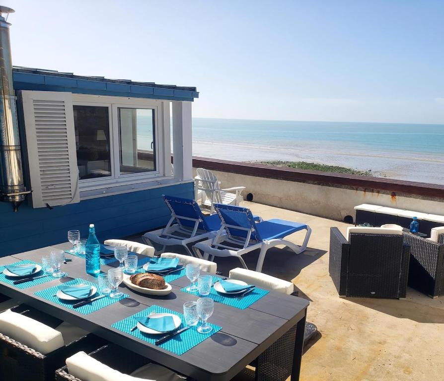 - une table et des chaises sur une terrasse donnant sur la plage dans l'établissement ARCADAMOUSSE Maison en bord de mer Granville baie du Mont Saint Michel, à Granville