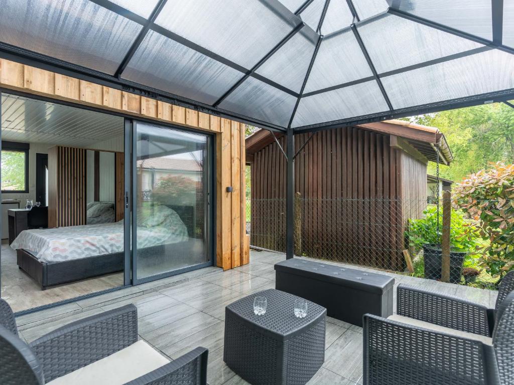 un patio grillagé avec un lit, une table et des chaises dans l'établissement Studio Neuf pour 2 à Parentis-en-Born – Ménage Inclus - FR-1-319-608, à Parentis-en-Born