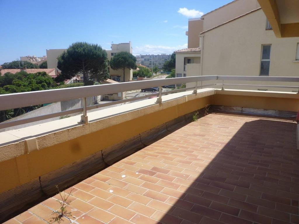 - un balcon d'un bâtiment avec une passerelle en briques dans l'établissement Appartement 3 Pièces avec Terrasse et Parking Sécurisé - FR-1-750-95, à Canet