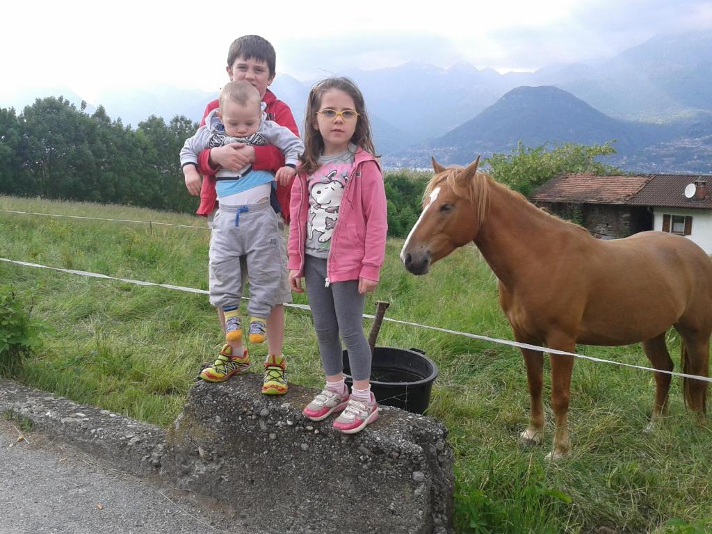zwei Kinder und ein Baby stehen neben einem Pferd in der Unterkunft B&B da-di in Colico