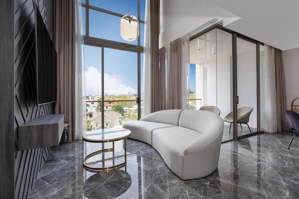 a living room with a white couch and a large window at Elite Atoll Serviced Apartments Phuket in Rawai Beach