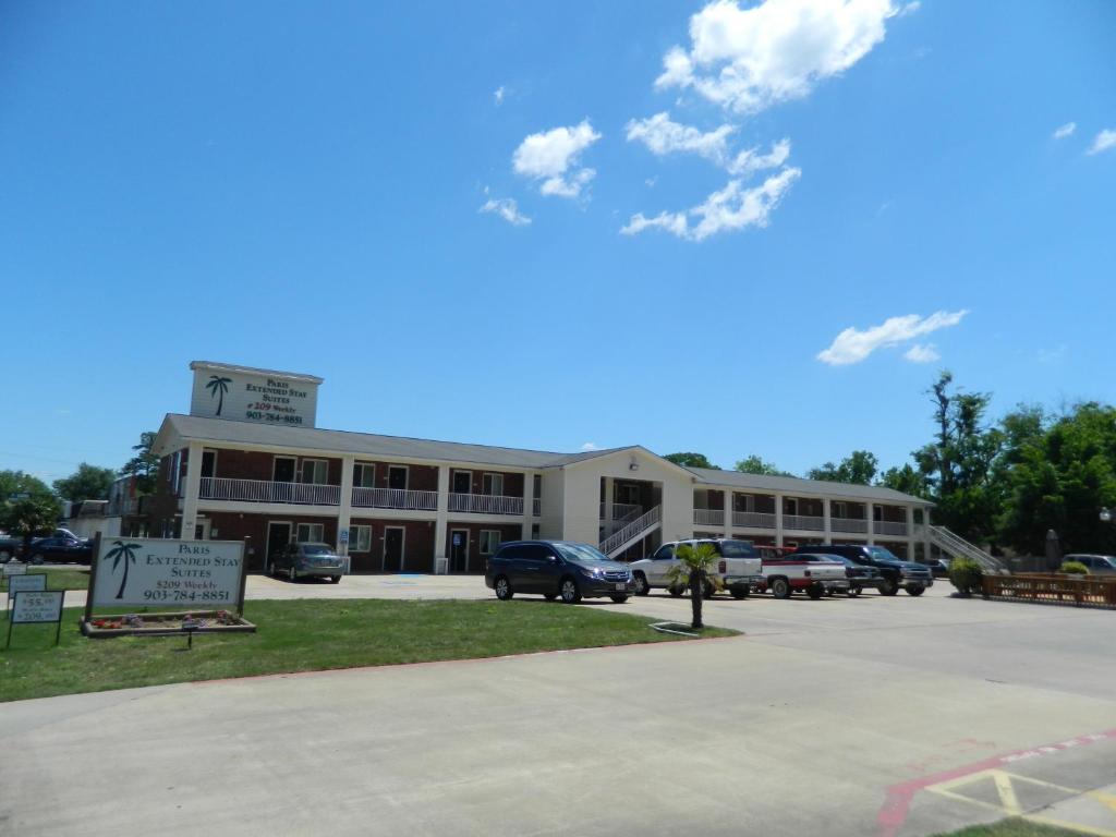 a large building with cars parked in a parking lot at Paris Extended Stay Suites in Paris