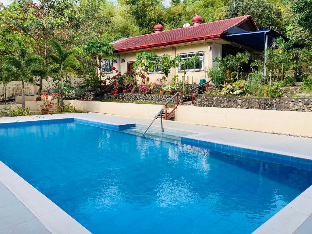 uma casa com uma piscina azul em frente a uma casa em The poolhouse at McKirdy's mango farm em Sison