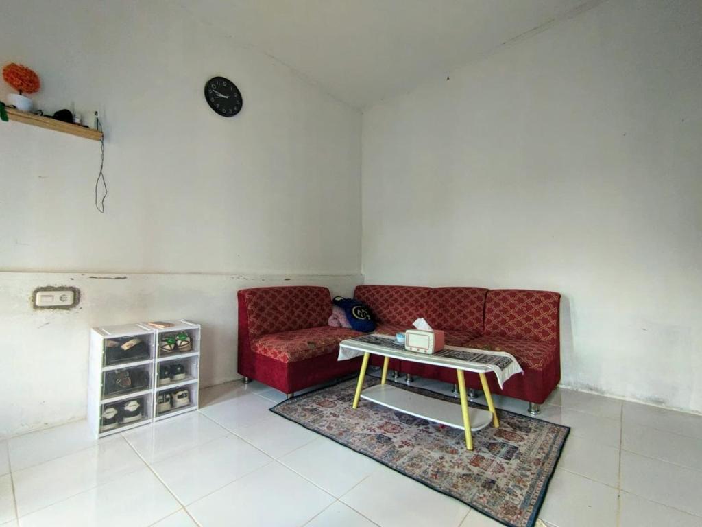 a living room with a red couch and a table at Rumah Liburan Sikabu-kabu in Airtabit