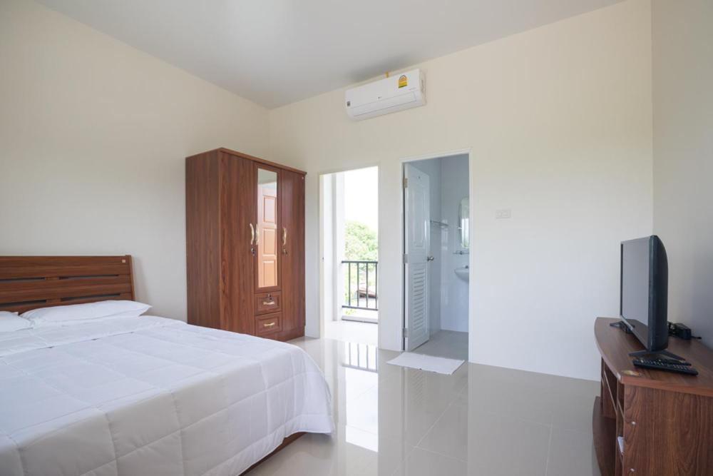 Un dormitorio blanco con una cama y un televisor. en Praew Place Phimai, en Ban Muang