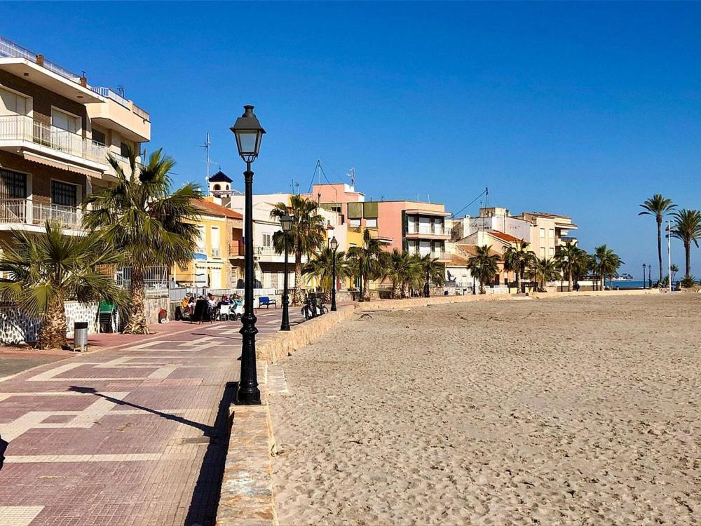 latarnia uliczna na plaży z palmami i budynkami w obiekcie 2 Bed Apartment 3 minutes from the beach in Los Alcazares w mieście Los Alcázares