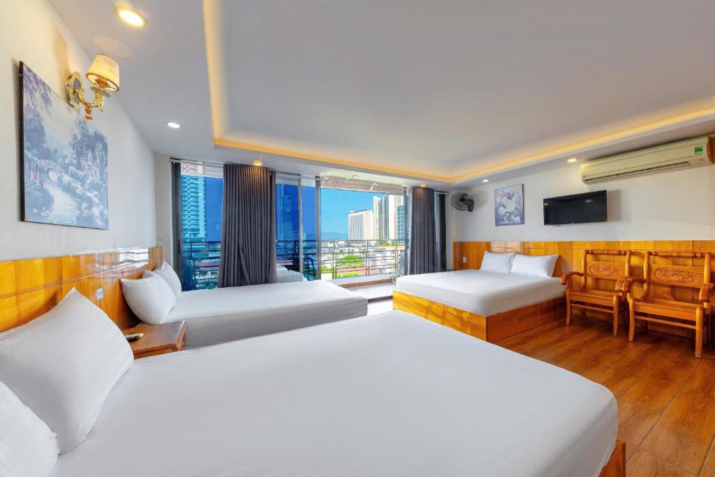 a hotel room with two beds and a balcony at Hằng Nga Hotel in Nha Trang