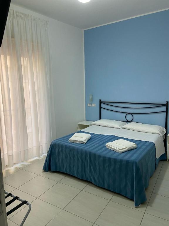 a bedroom with a blue bed with towels on it at Maniel Beach Hotel in Letojanni