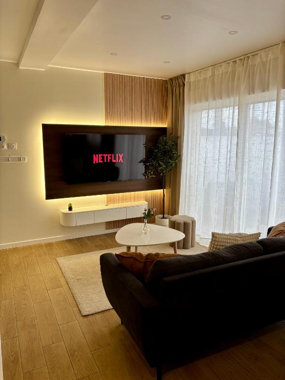 un salon avec un canapé et une télévision dans l'établissement La Millésime, à Saint-André-de-Cubzac