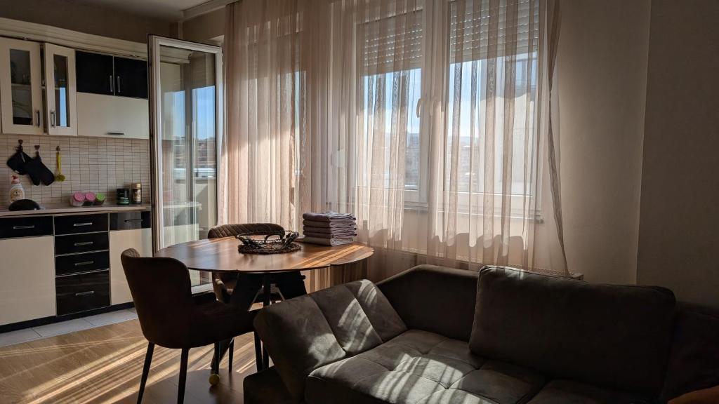 a living room with a table and a couch at Cozy apartment in Prishtinë
