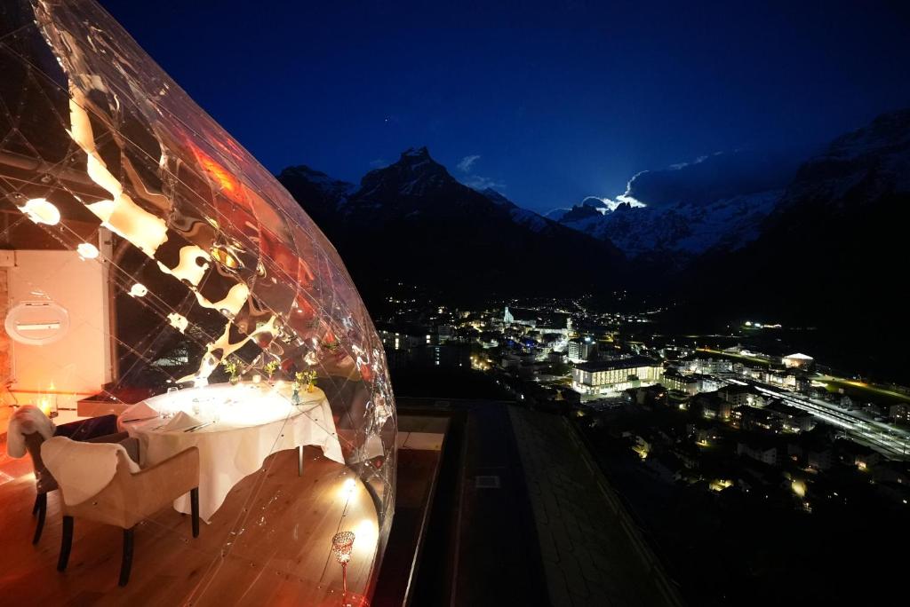 a table and chairs on a balcony at night at Hotel Waldegg - Adults only in Engelberg