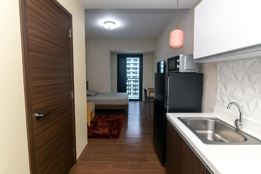 a kitchen with a sink and a refrigerator at The Plush Pad Makati Ayala Views 300MB WiFi 1940 in Manila