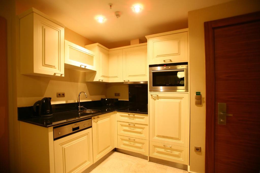 a kitchen with white cabinets and a sink and a microwave at Goldcity Hotel in Kargicak