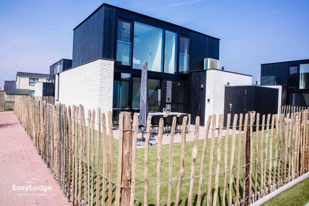 ein Haus mit einem Holzzaun davor in der Unterkunft Nieuwe vakantiewoning met tuin dicht bij strand in Middelkerke