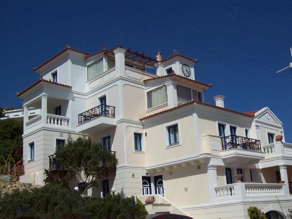 Biały budynek z zegarem na górze w obiekcie Kalimera Hotel w Poros