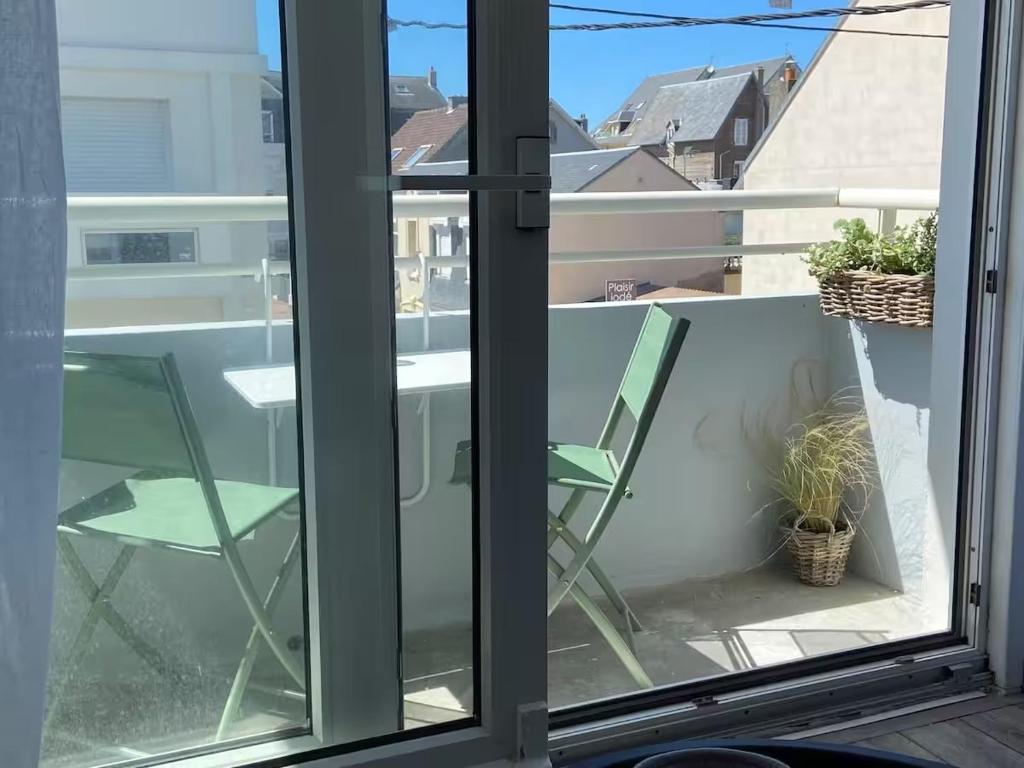 une fenêtre en verre avec une chaise et une table sur un balcon dans l'établissement Appartement avec balcon au coeur des commerces et de la Plage de Berck, à Berck-sur-Mer