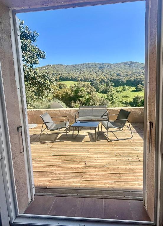 Une porte ouverte s'ouvre sur une terrasse avec une table et des chaises. dans l'établissement Campana, à Sartène