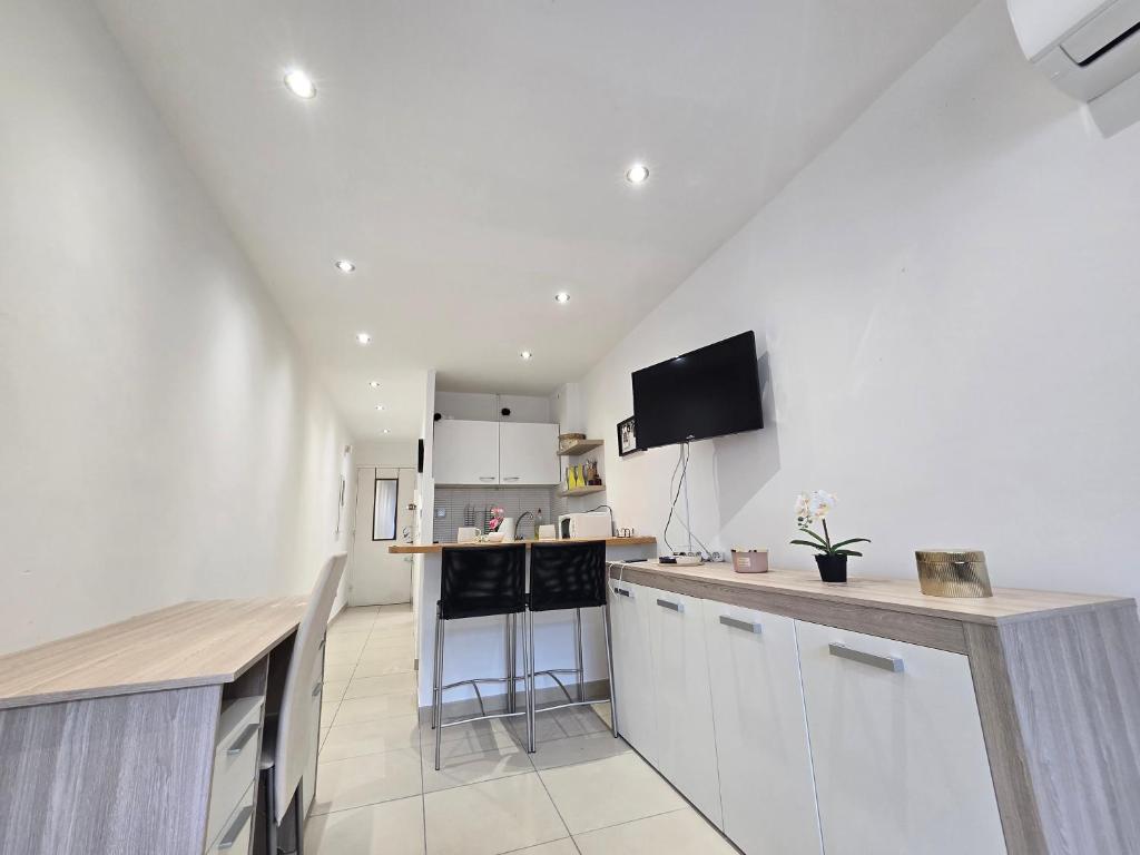 Il comprend une cuisine avec des placards blancs et une télévision murale. dans l'établissement Sunny Prom Studio, à Nice