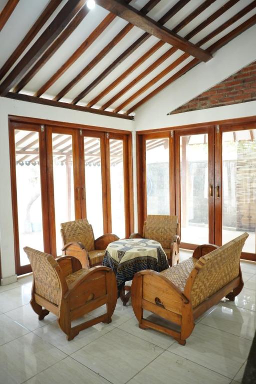 a room with chairs and a table and windows at Joglo Turen Villa in Ngaglik