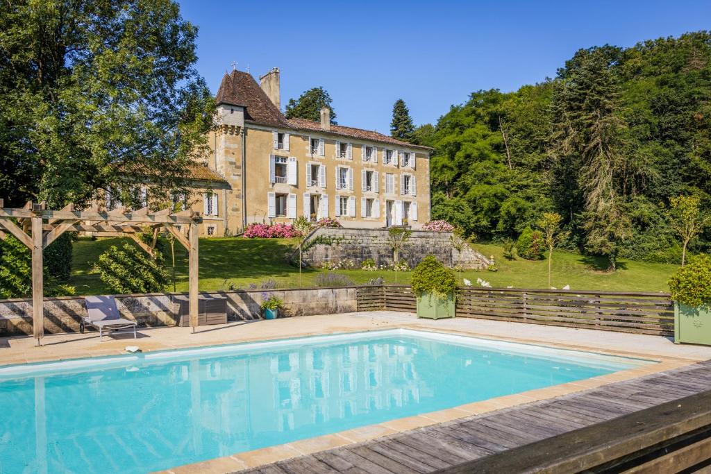 a swimming pool in front of a large house at Chateau de la Guerinchie, beautiful 7 bedroom castle in the heart of the Dordogne in Thiviers