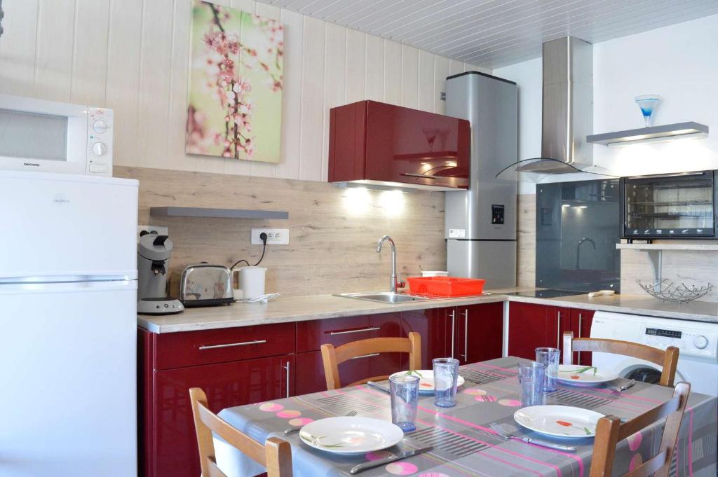 une cuisine avec une table et des chaises et une cuisine avec des placards rouges dans l'établissement Appt Studio 4 couchages - CAP D'AGDE CT090-292, au Cap d'Agde