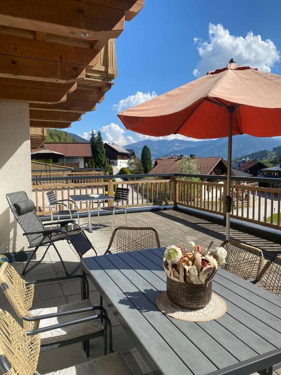 a picnic table with an umbrella and a basket of flowers at Alpinresort Kaprun 3 in Kaprun