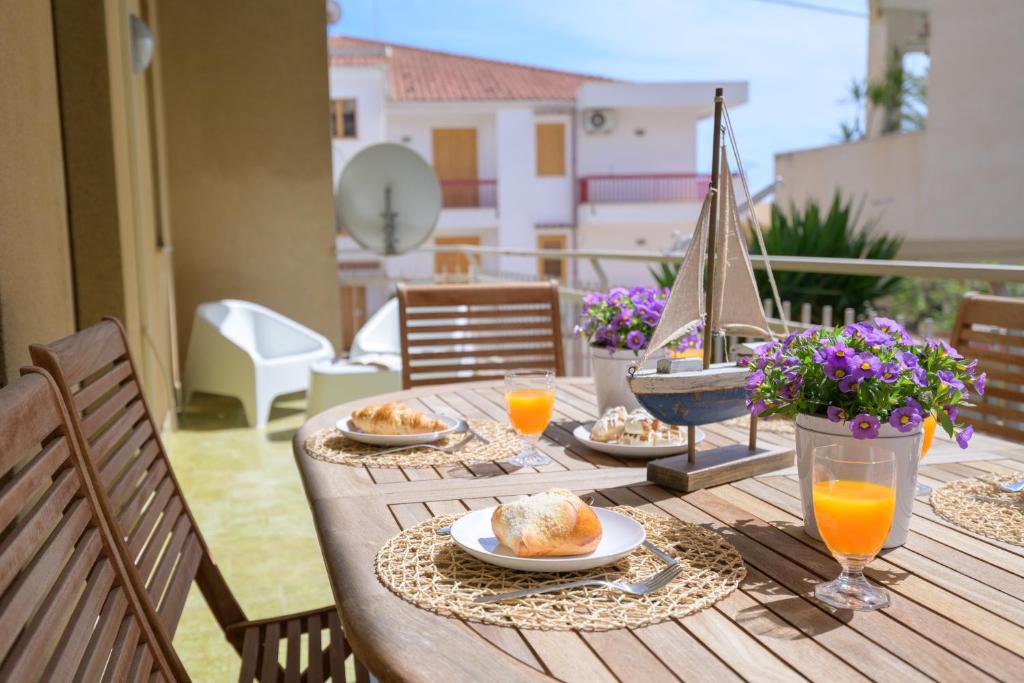 a wooden table with plates of food and orange juice at siciliacasevacanze - Marina Domus 35 in Marina di Ragusa
