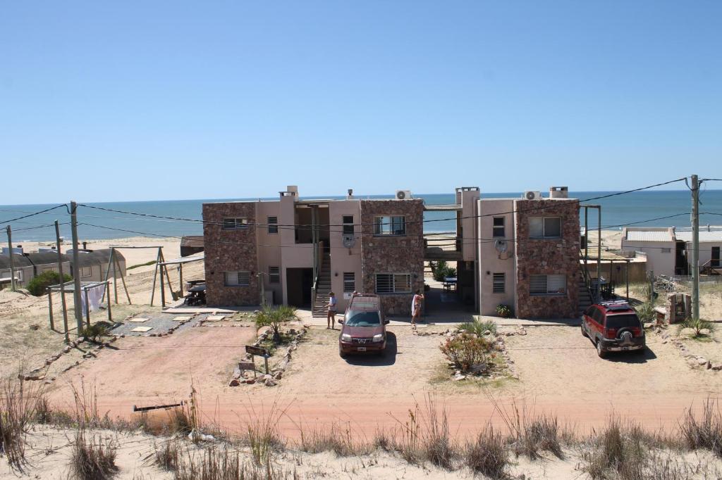 un bâtiment avec deux voitures garées devant lui dans l'établissement Arenas del Mar, à Punta del Diablo