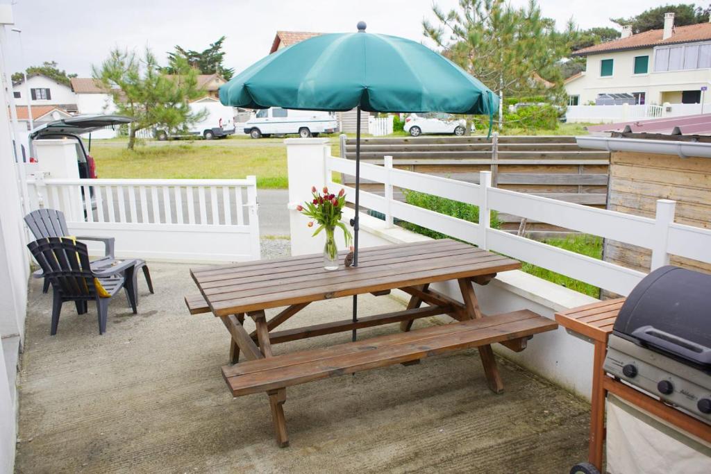 a picnic table with an umbrella on a deck at Maison 4 personnes tout confort à 300m de la plage - Clim & Wifi in Mimizan-Plage