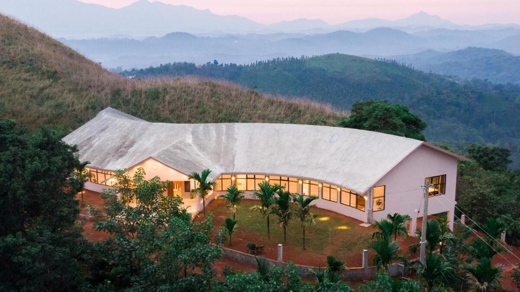una casa en una colina con montañas al fondo en A Hilltop Nature Retreat in Wayanad, en Tindummal