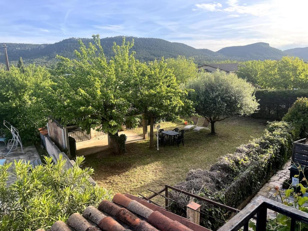 une vue d'un jardin avec des arbres et des tables dans l'établissement Charmante retraite champêtre, à Bagnols-en-Forêt
