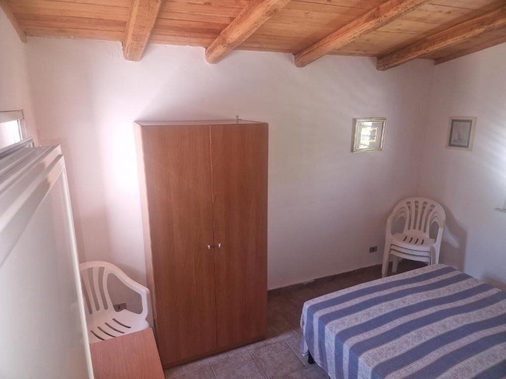 1 Schlafzimmer mit einem Bett, einem Schrank und 2 Stühlen in der Unterkunft Casa vacanza sul mare 1 in Santa Caterina Dello Ionio Marina