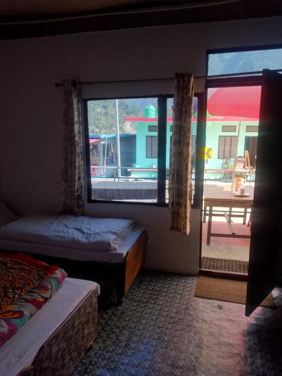 a room with two beds and a window with a patio at Kanhaiya Hotel in Sonprayag