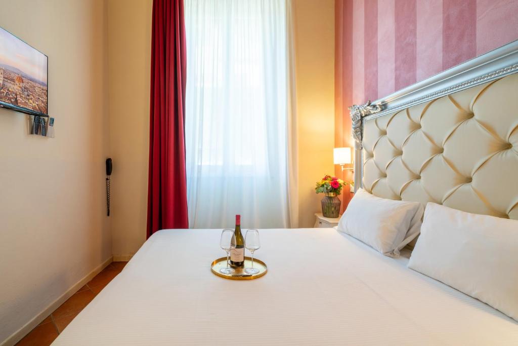 a bed with a bottle of wine and a glass on it at Residenza Conte di Cavour & Rooftop in Florence