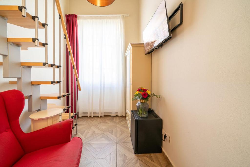 a living room with a red chair and a television at Residenza Conte di Cavour & Rooftop in Florence