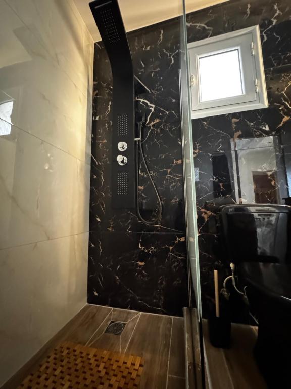 e bagno con doccia e parete in marmo nero. di Giannis Philoxenia a Paloúkia