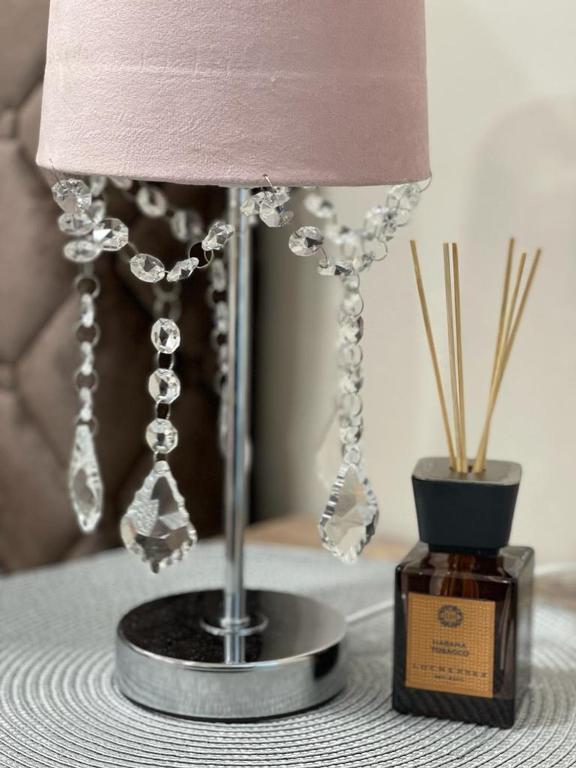 a lamp sitting on a table next to a bottle of perfume at Palanga Old Town in Palanga