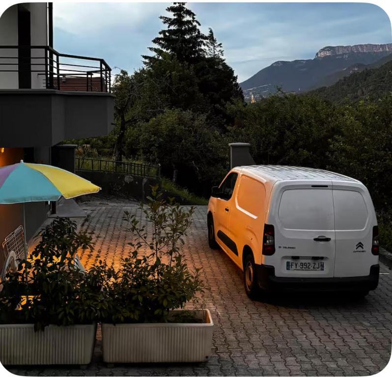 a white van parked next to a building with an umbrella at Appartement esprit jeune in Seynod