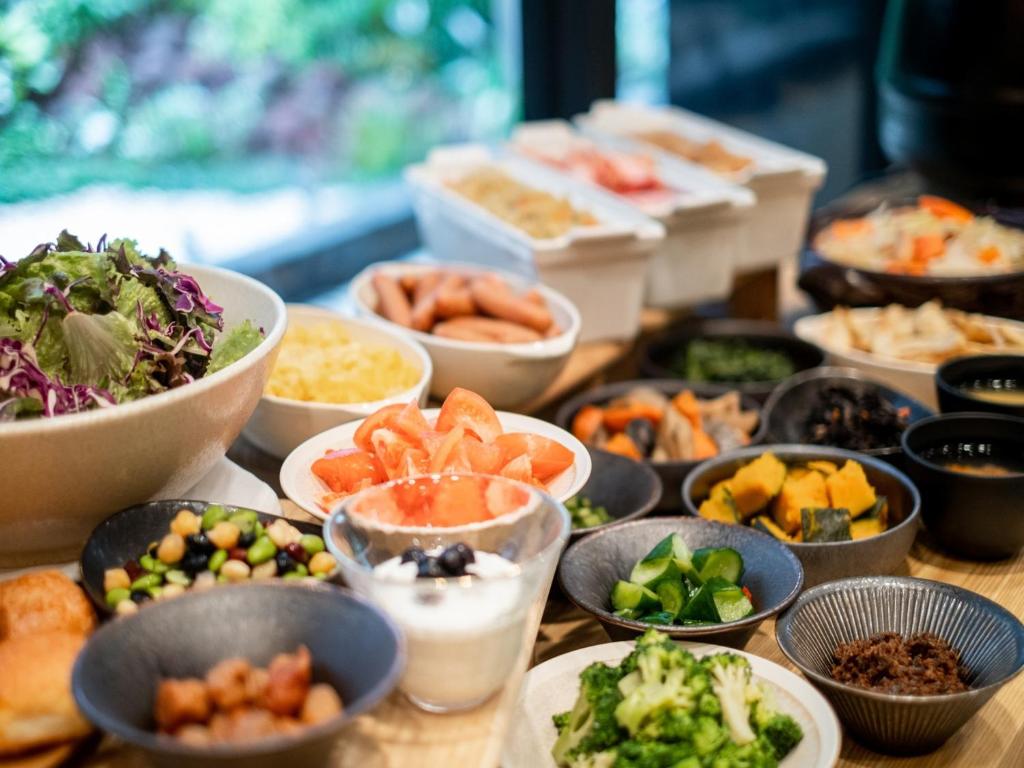 einen Tisch mit Schalen verschiedener Arten von Lebensmitteln in der Unterkunft APA Hotel PRIDE Akasaka Kokkaigijidomae in Tokio