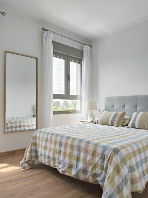 a white bedroom with a bed with a plaid blanket at La Casa del Muelle in Huelva