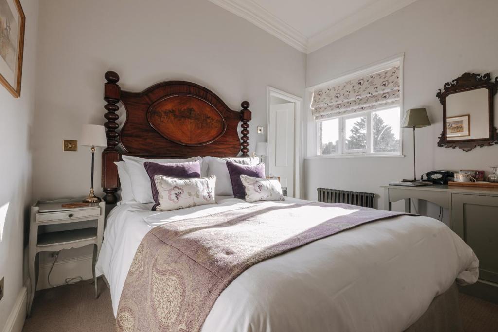 a bedroom with a large bed with a wooden headboard at Victoria in Holkham