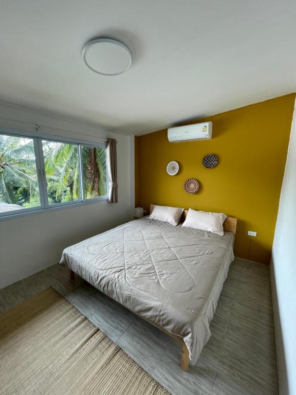 a bedroom with a bed with a yellow wall at Unity coliving in Thong Sala