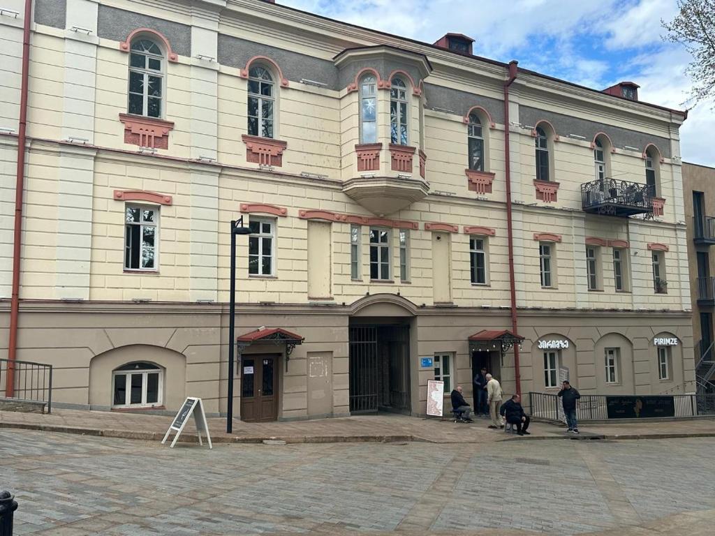 Un gran edificio con gente parada afuera. en orbeliani cozy flat, en Tiflis